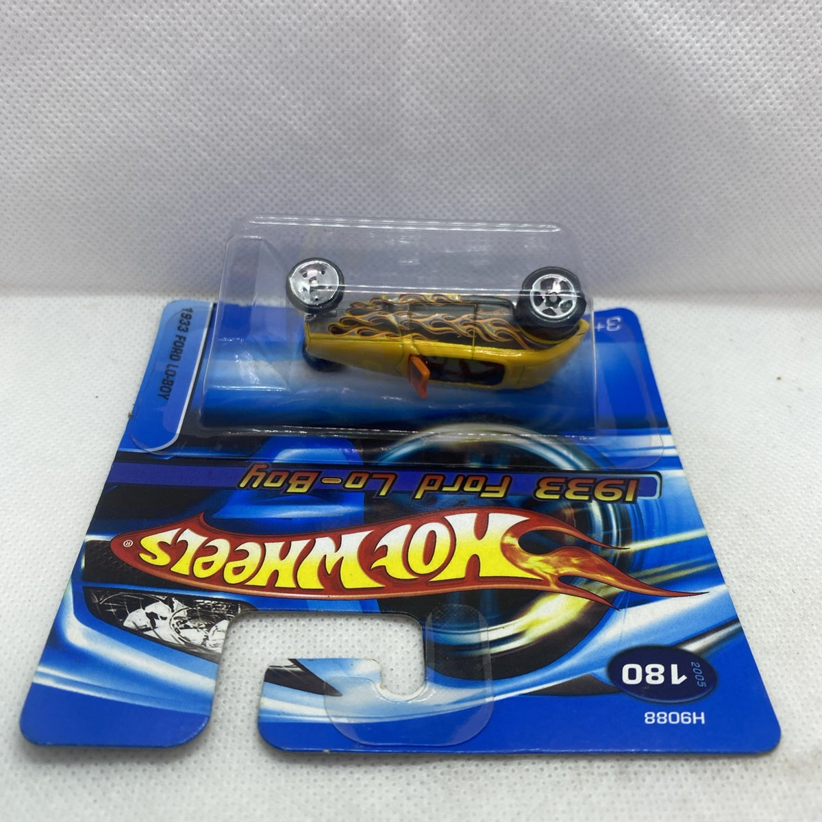 Blue blister card featuring a yellow die-cast toy car with chrome wheels and orange stripe