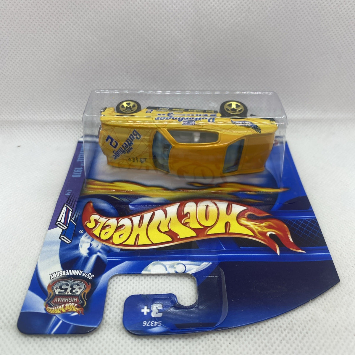 Hot Wheels die-cast yellow car in sealed blister pack, side/top view with wheels visible