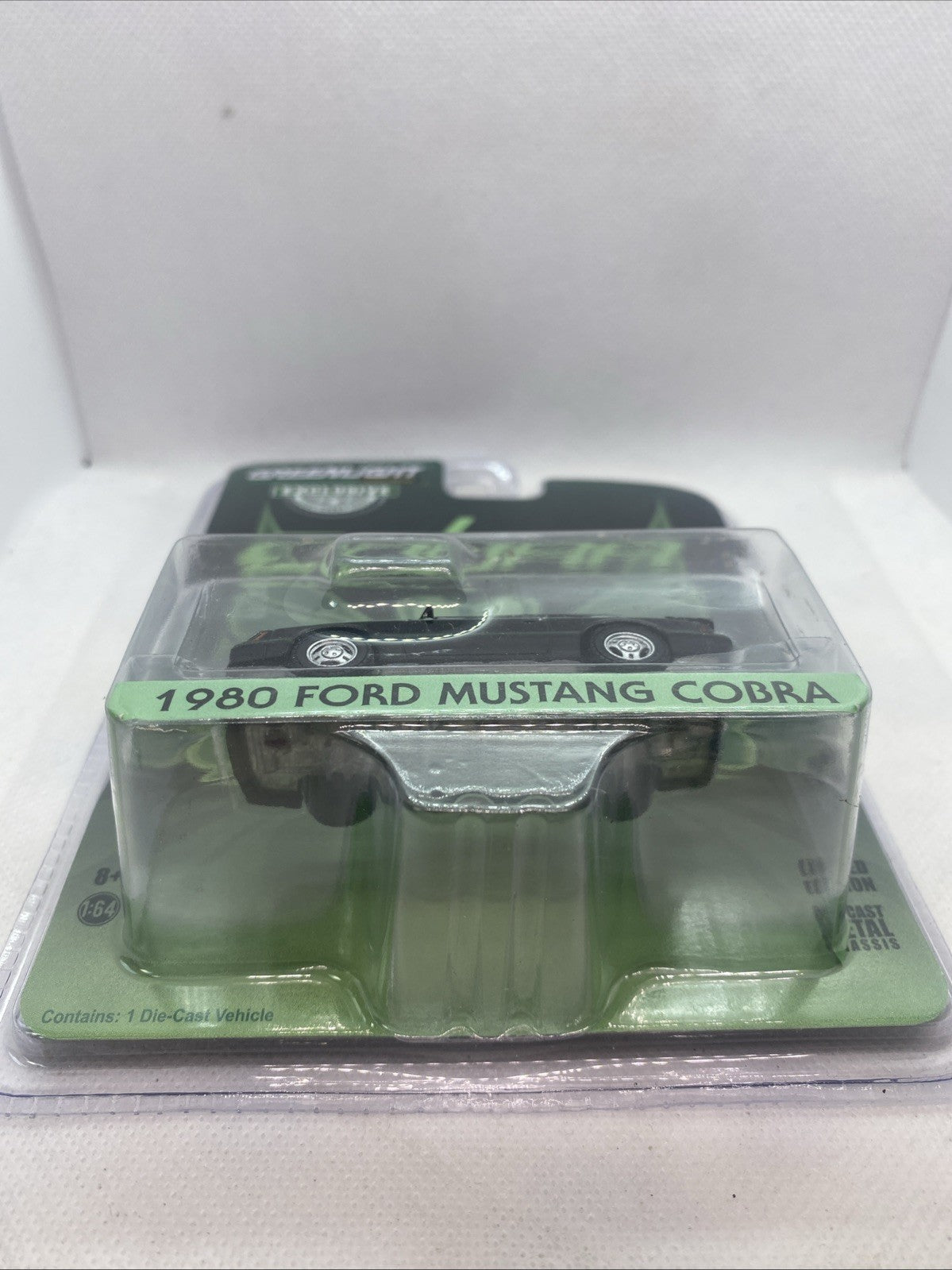 Die-cast model car in clear blister with green base and molded black body
