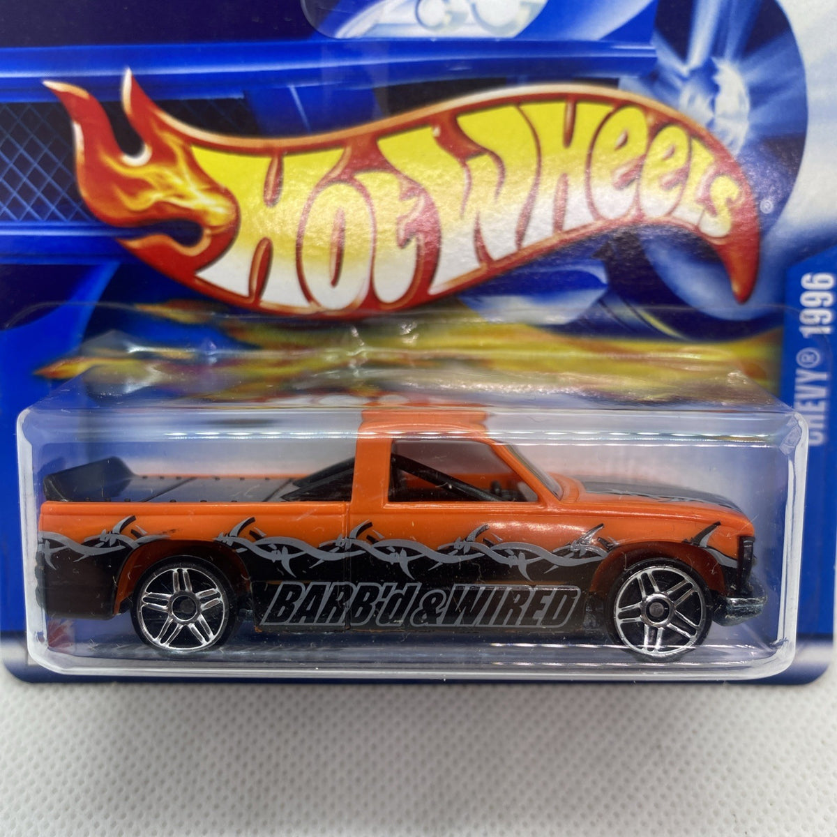 Hot Wheels orange die-cast pickup close-up on blister card, flame logo