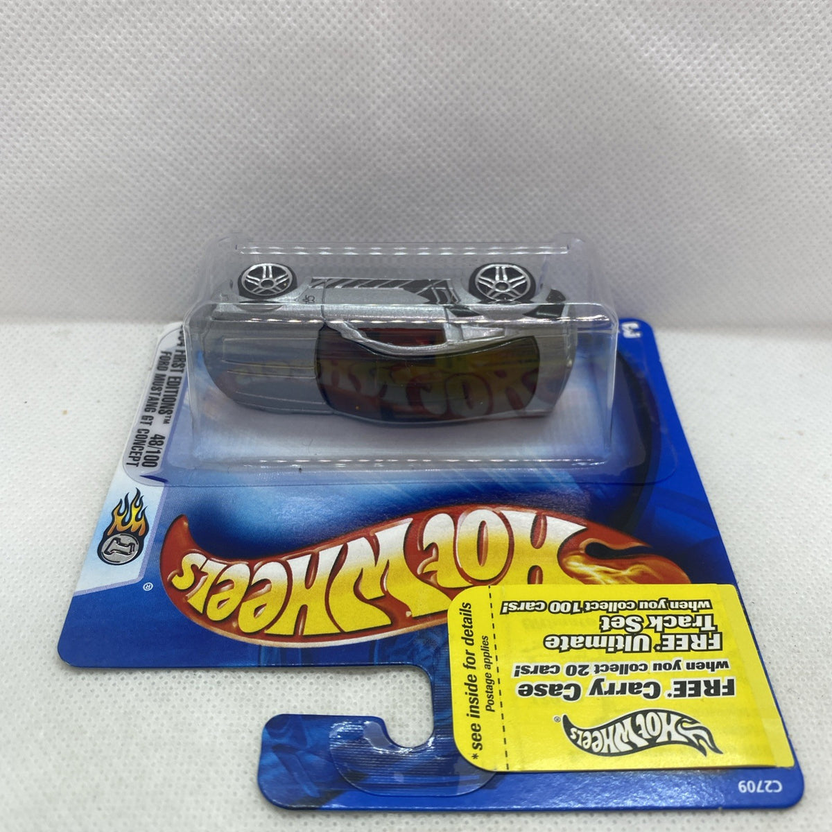 Hot Wheels die-cast car in clear blister, silver/gray body and black graphics, side view