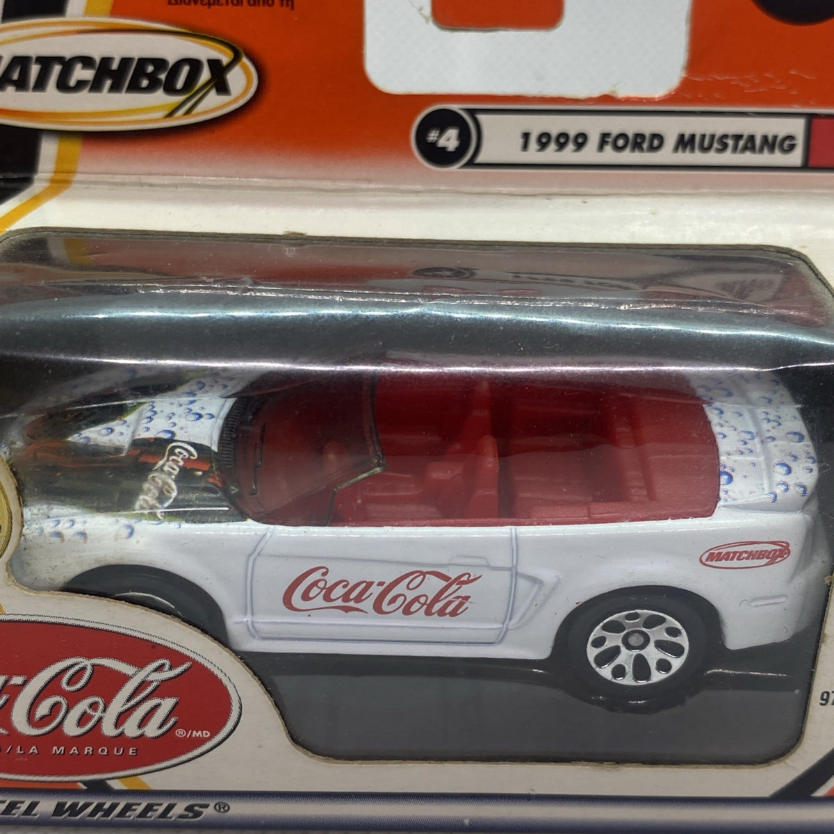 Close-up of white Coca-Cola die-cast Ford Mustang inside clear blister packaging