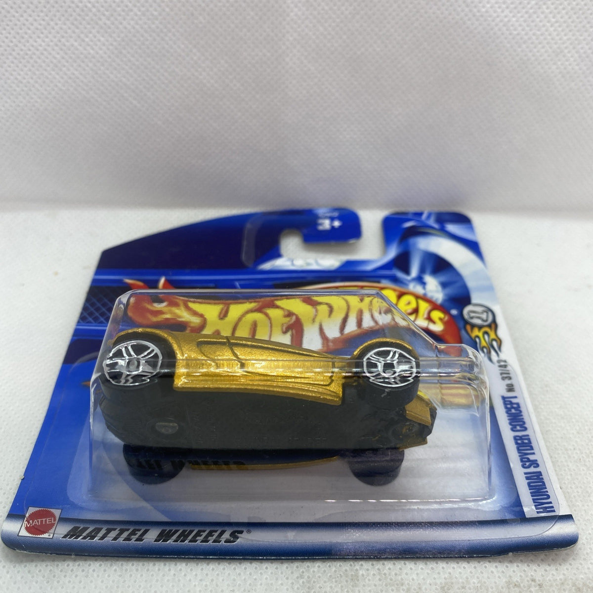 Hot Wheels gold die-cast car in clear blister pack, side view on blue card