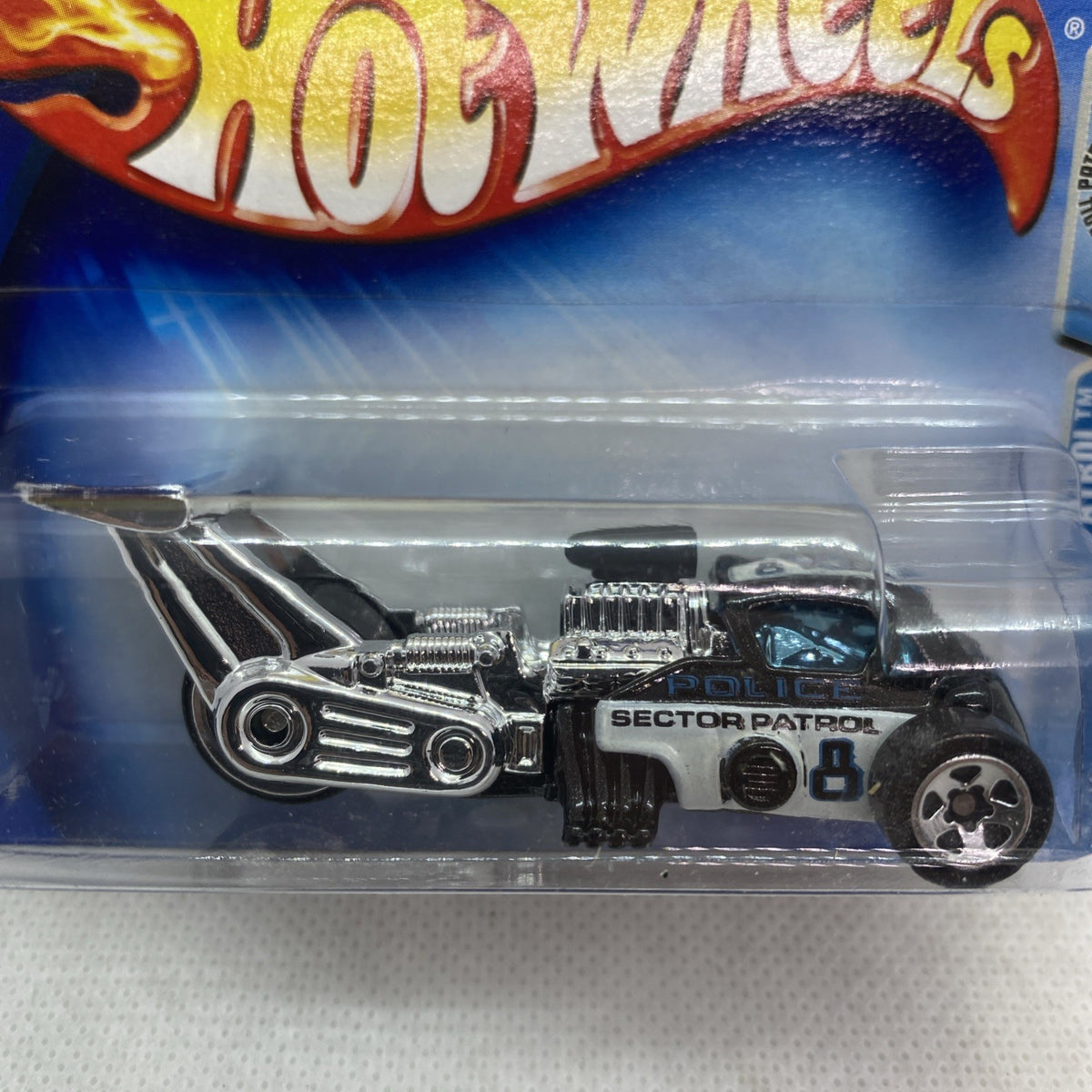 Hot Wheels die-cast toy car close-up in blister, black body with chrome front and engine