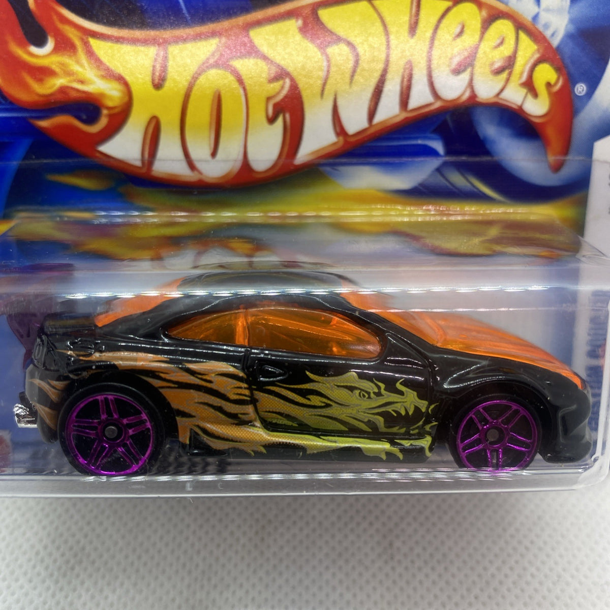 Hot Wheels die-cast car close-up in blister: black body with green flames and purple wheels