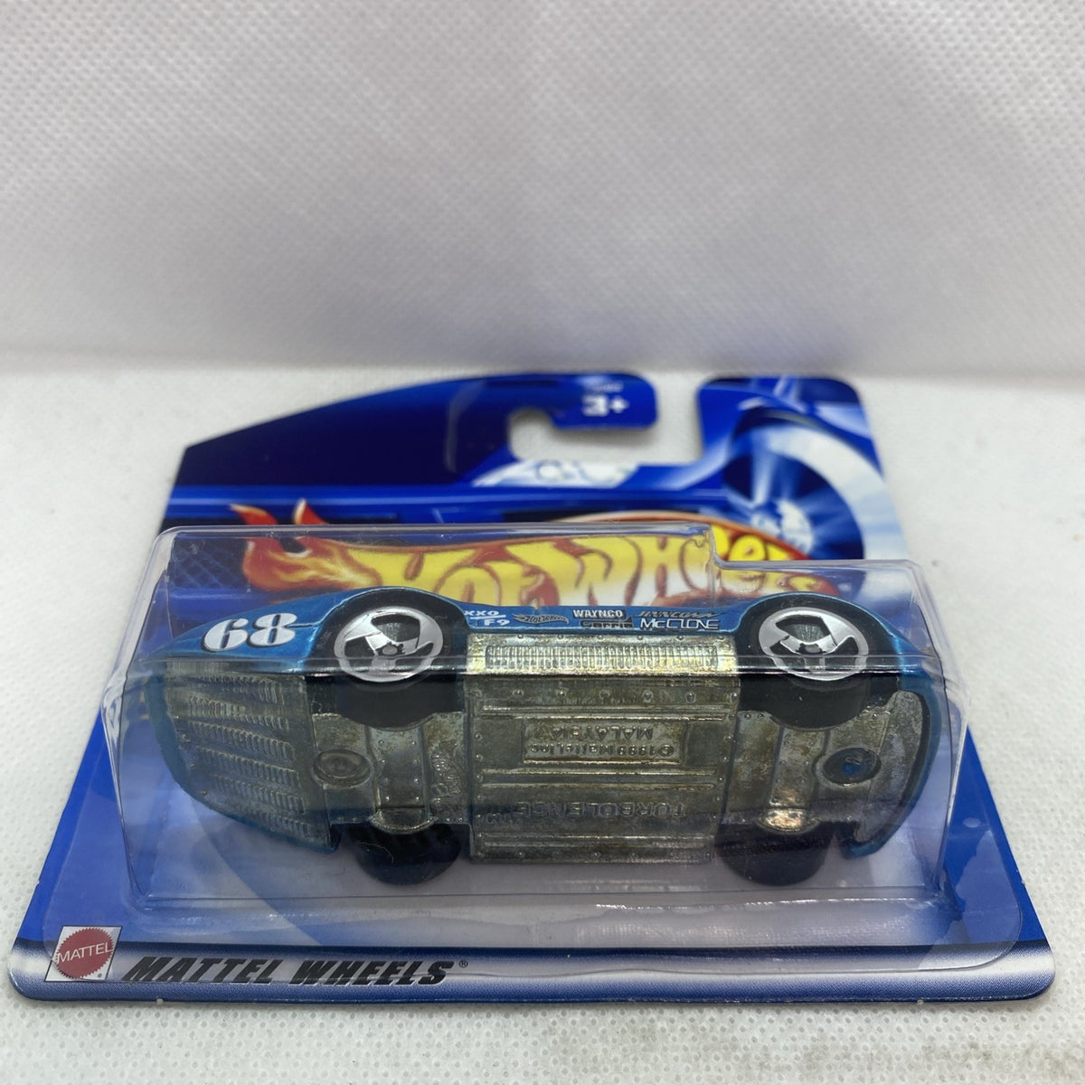 Blue Hot Wheels die-cast car in clear blister, side view with black wheels and engine grille