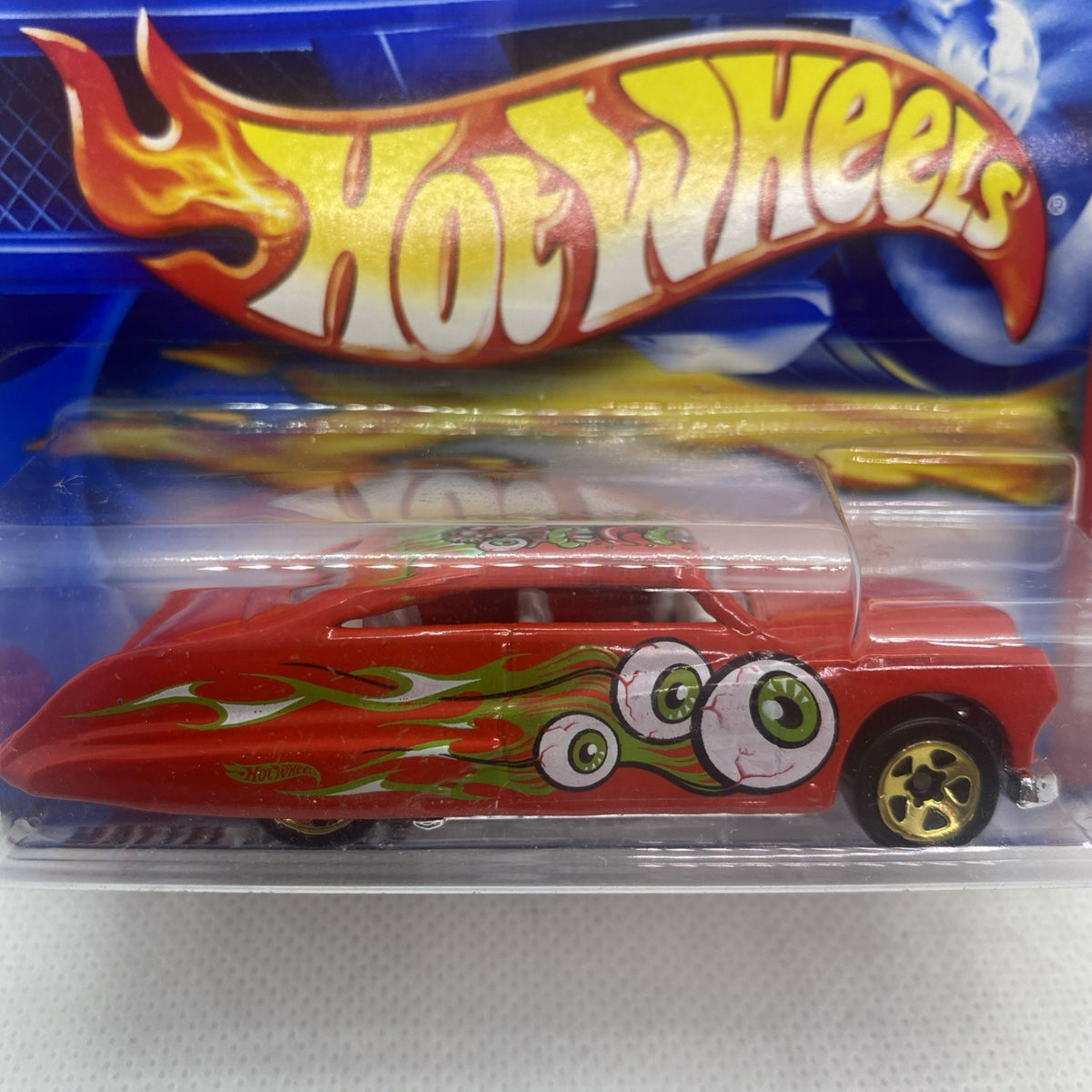 Close-up of Hot Wheels red monster car in clear blister, green flame graphics and gold wheels