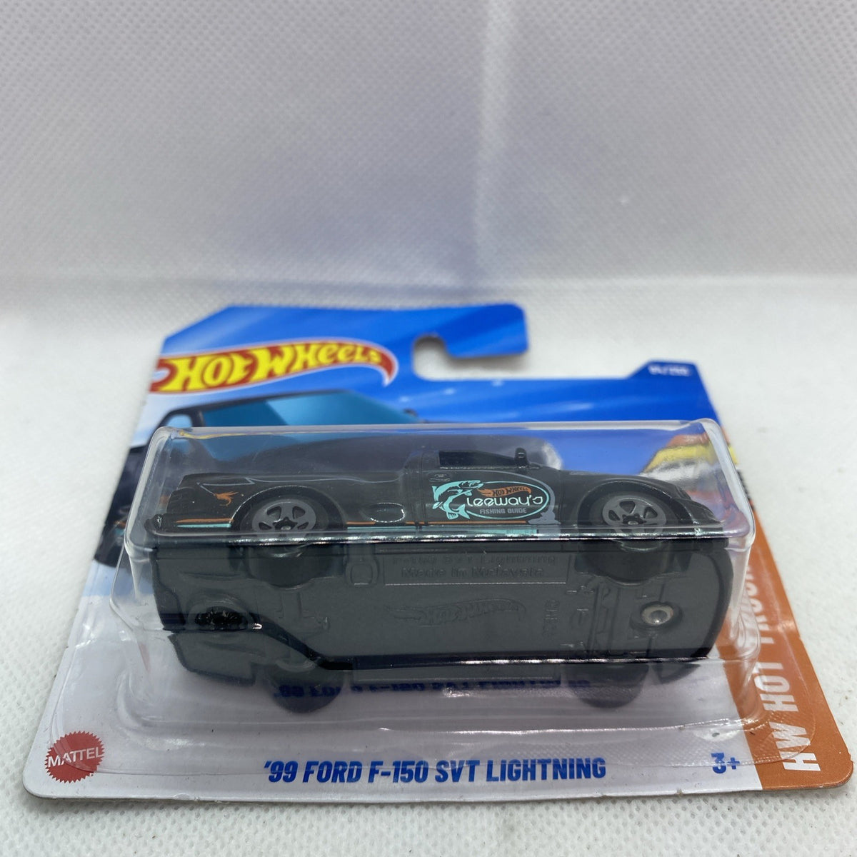 Hot Wheels die-cast pickup in blister, black body with teal logo and front grille.