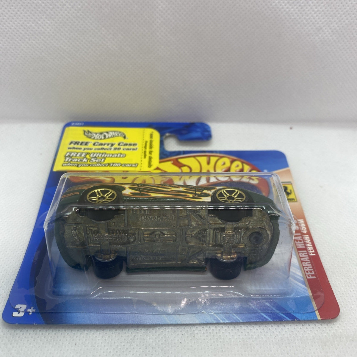 Die-cast sports car in blister pack, green with gold flames, wheels visible