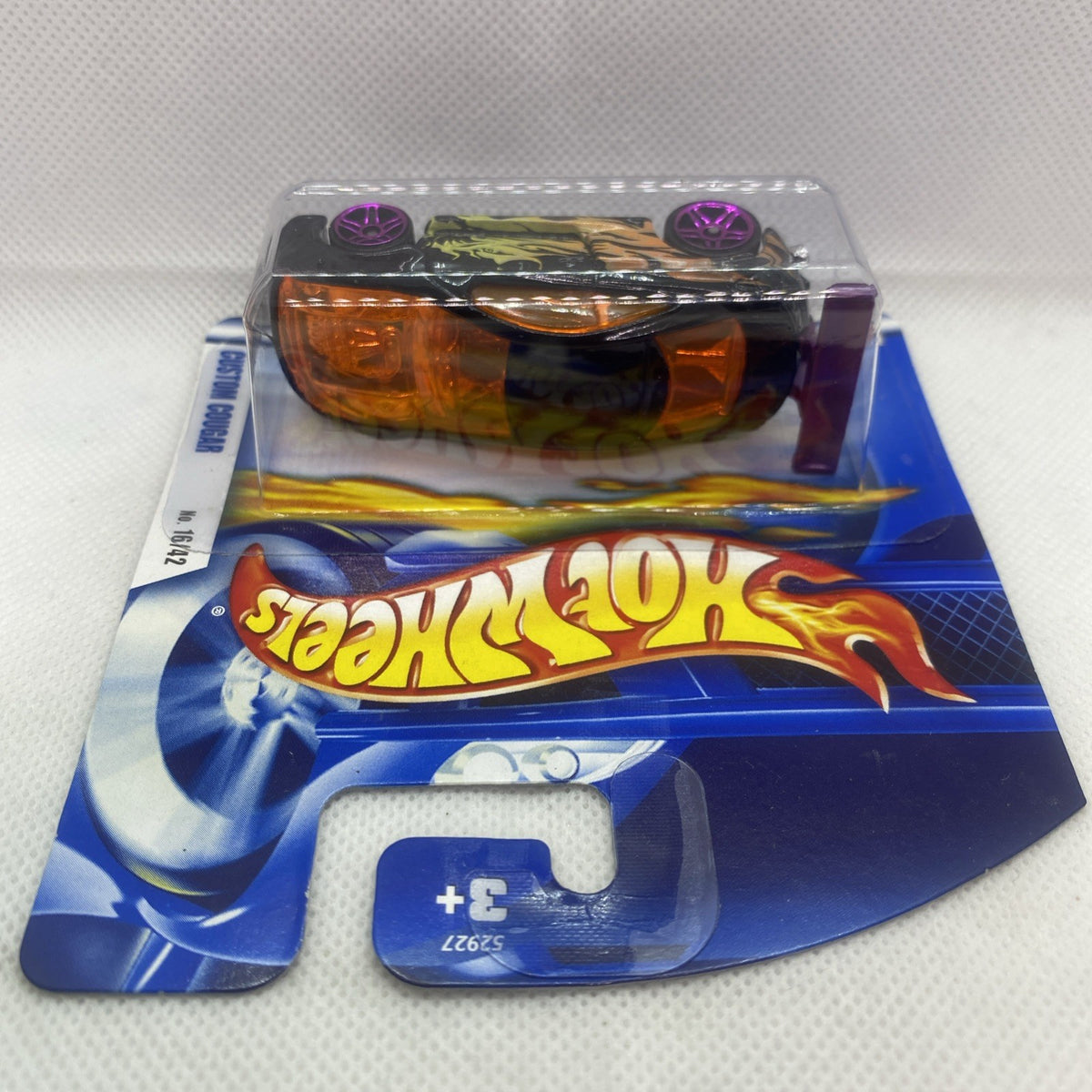 Hot Wheels blister pack with black-and-orange die-cast car, purple wheels, and top card art