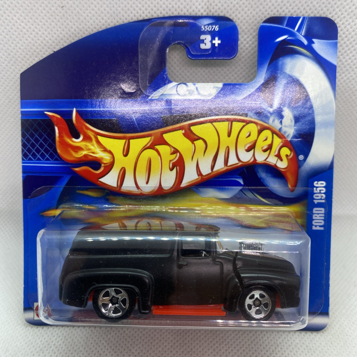 Hot Wheels die-cast truck in blue blister with flames graphics, black body, red stripe