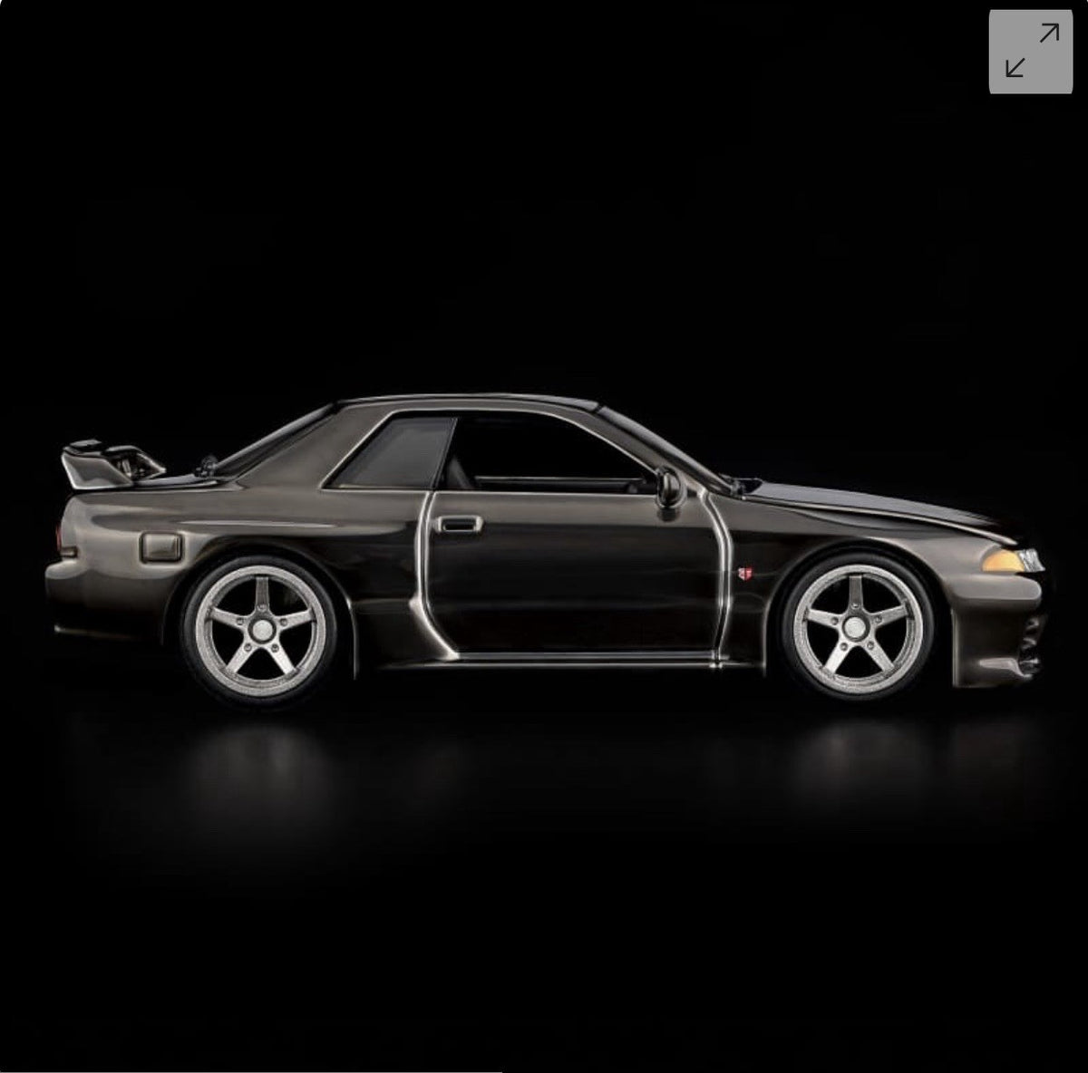 Die-cast sports car model, black side profile with white-spoke wheels and door trim