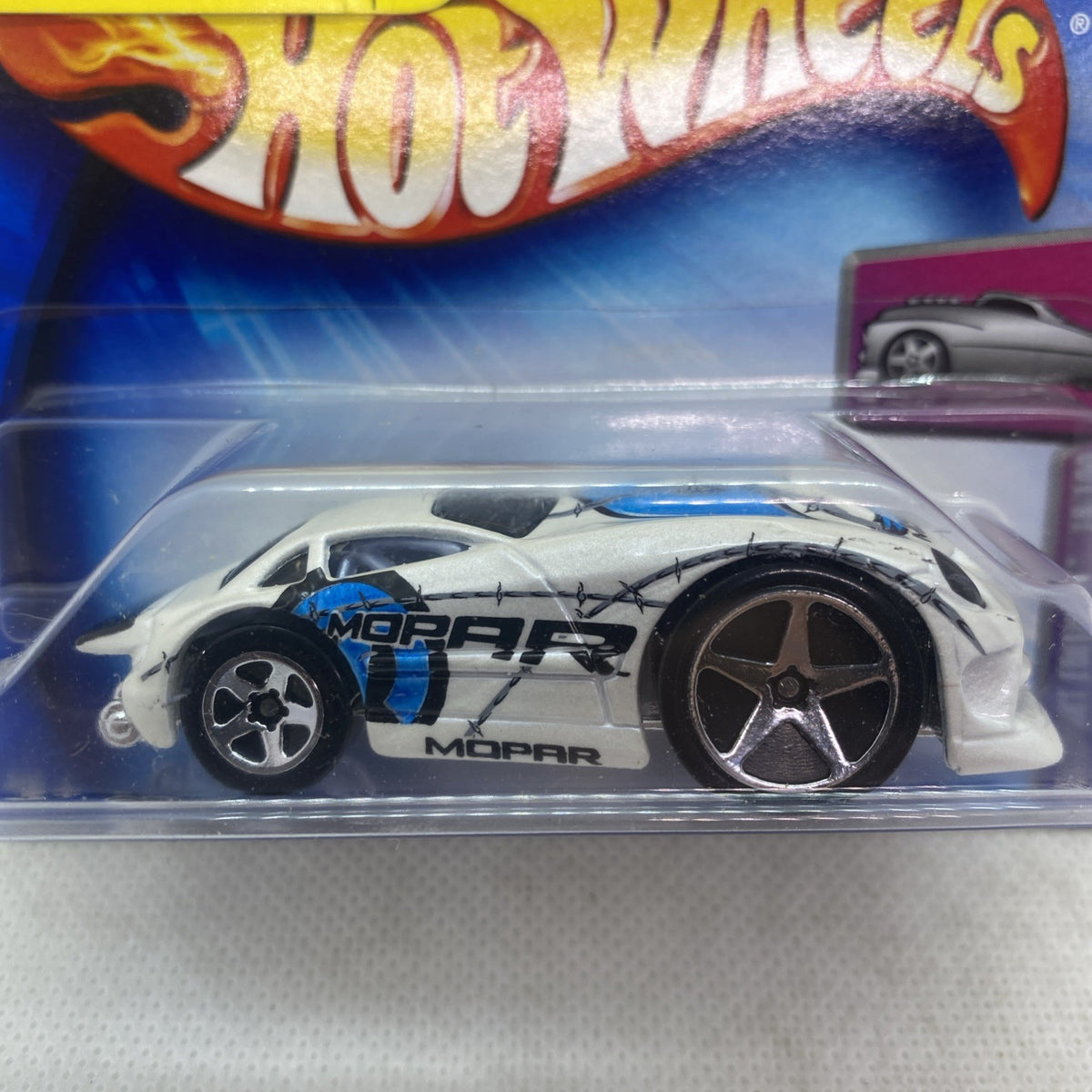 Hot Wheels race car close-up in blister pack, white body with black wheels and star grille