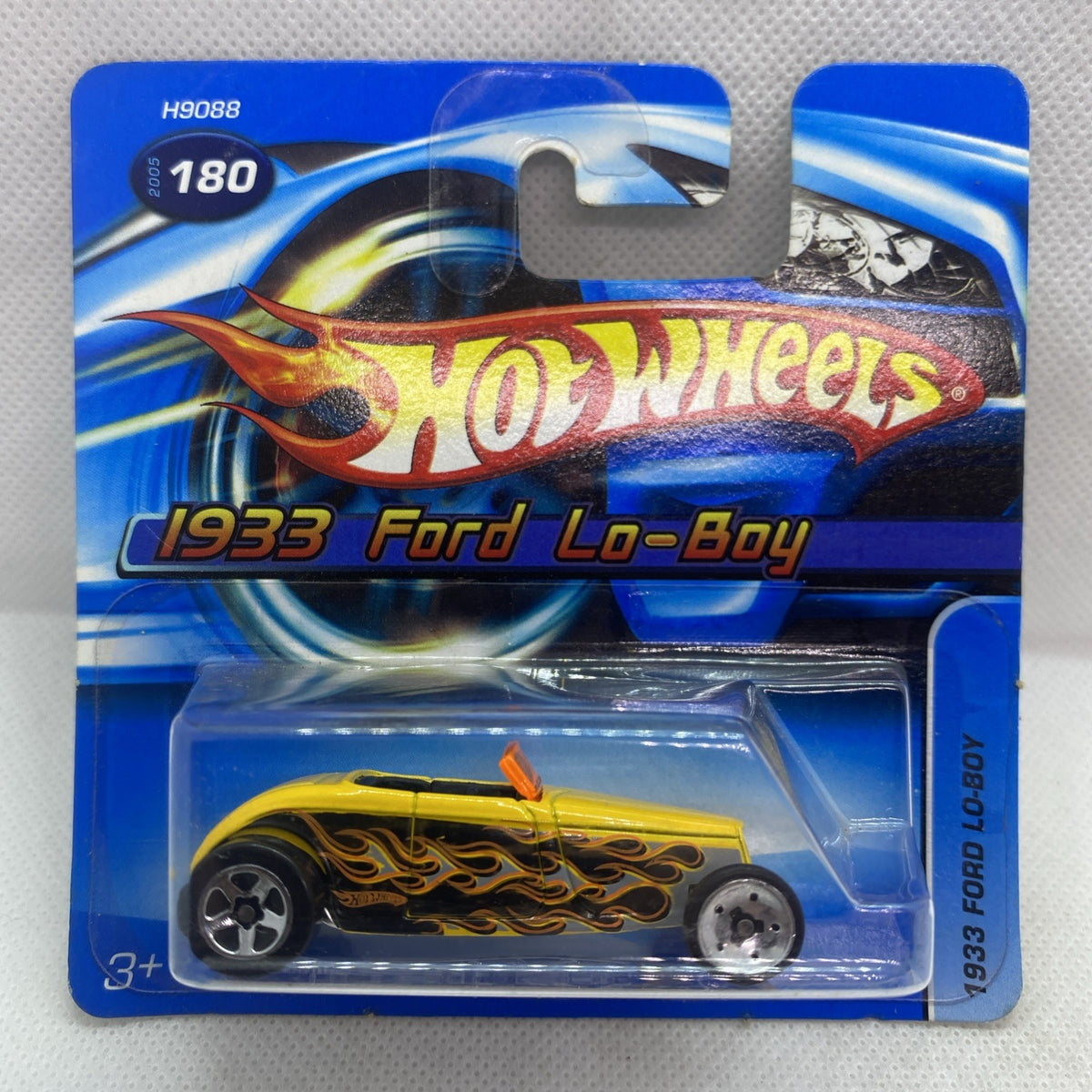 Yellow die-cast toy car blister pack with flame graphics and silver wheels