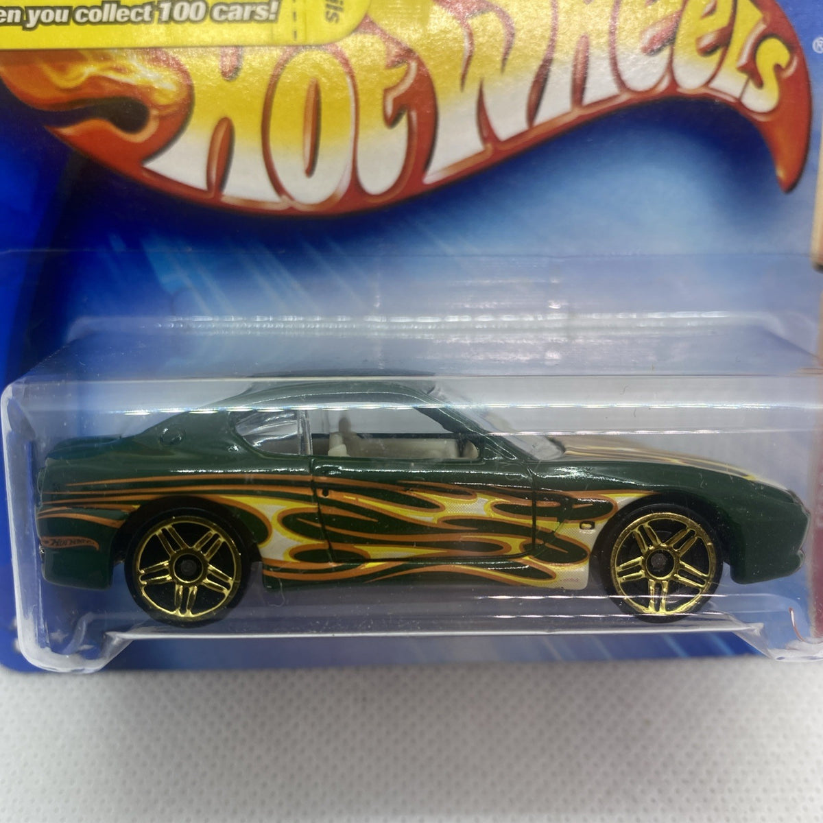 Close-up of die-cast sports car, green body with gold flame decals in blister