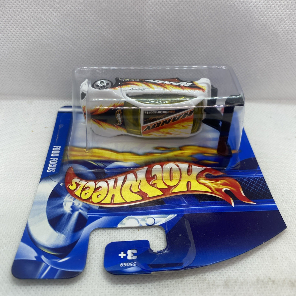Hot Wheels die-cast Ford Focus car in blister pack, angled view, white with flame graphics.