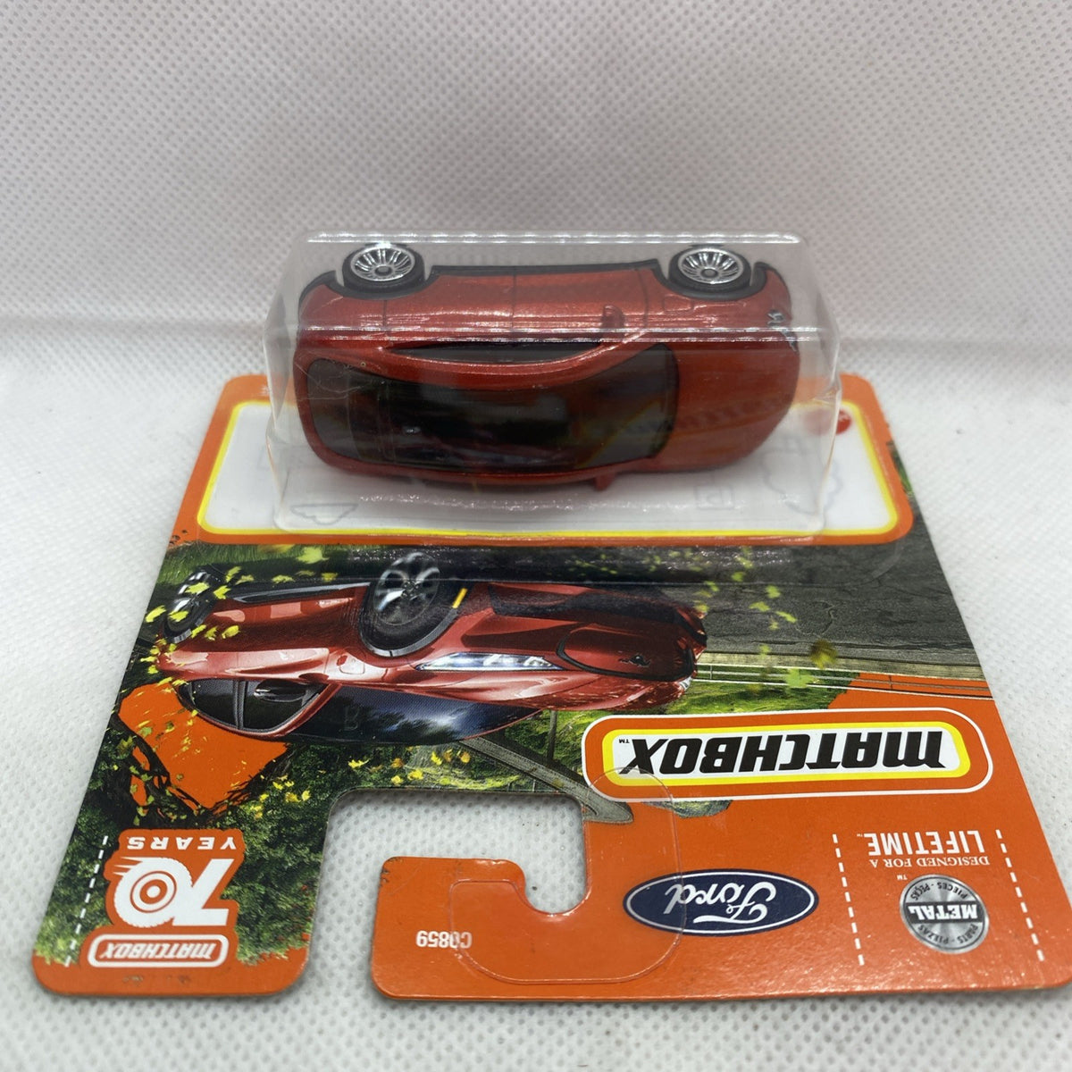 Orange and black blister card with red-brown toy sports car showing front view