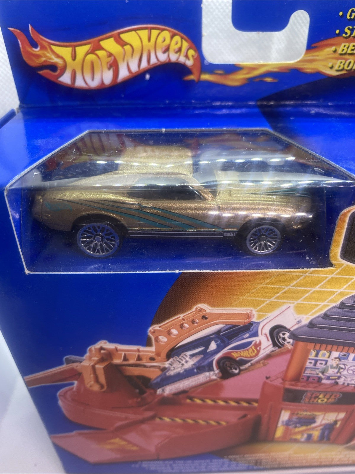 Hot Wheels die-cast car in clear blister with orange base and station pieces