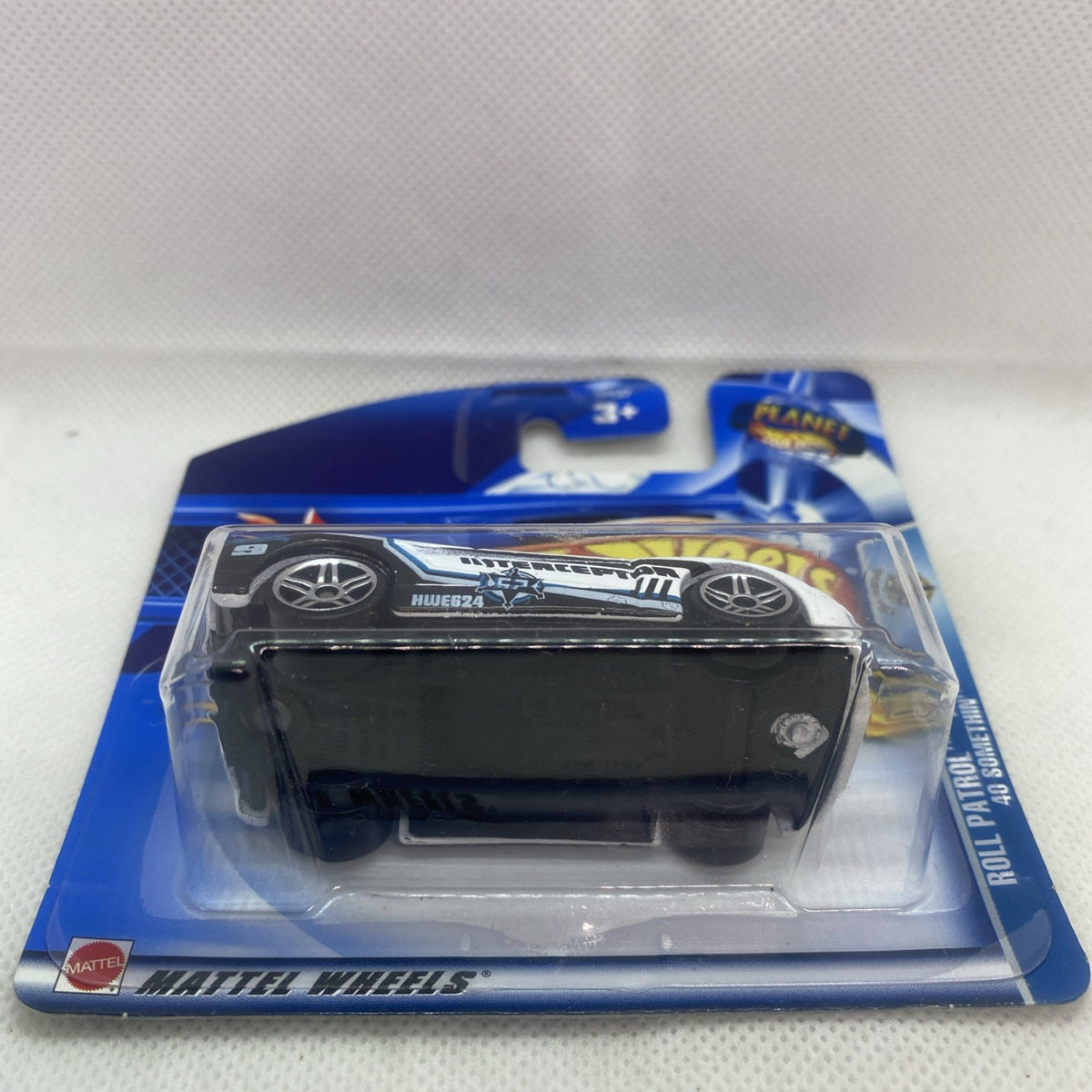 Hot Wheels die-cast car blister card, side view with black wheels and dark base