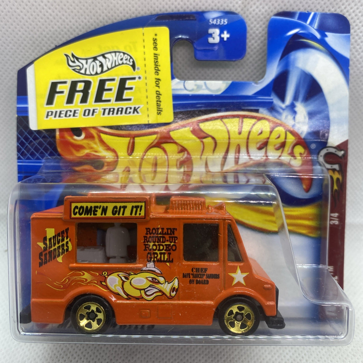 Orange Hot Wheels toy truck in clear blister pack with flame graphics and gold wheels