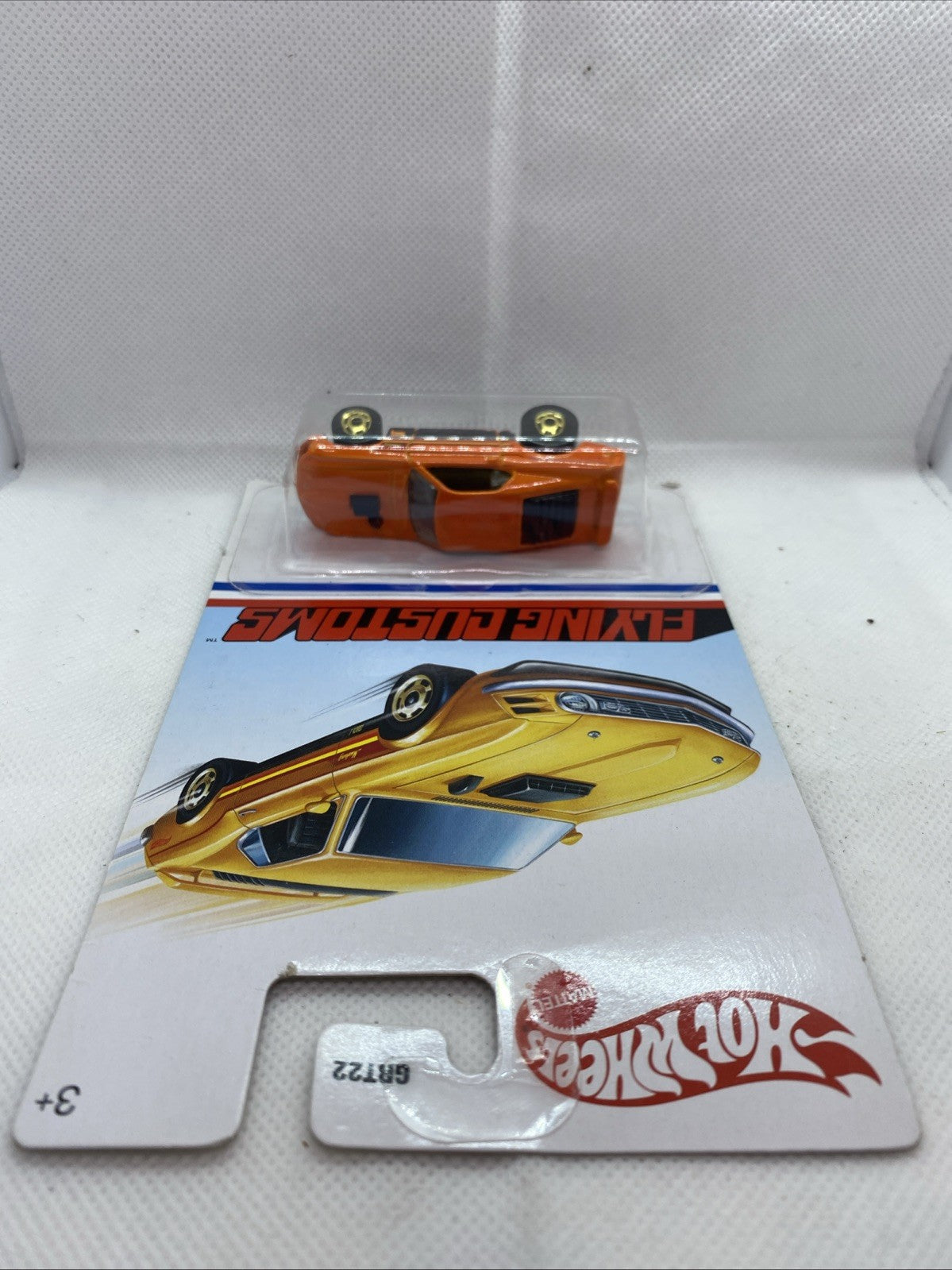 Hot Wheels '70 Ford Mustang Mach 1 die-cast on Flying Customs card, orange-and-yellow car view