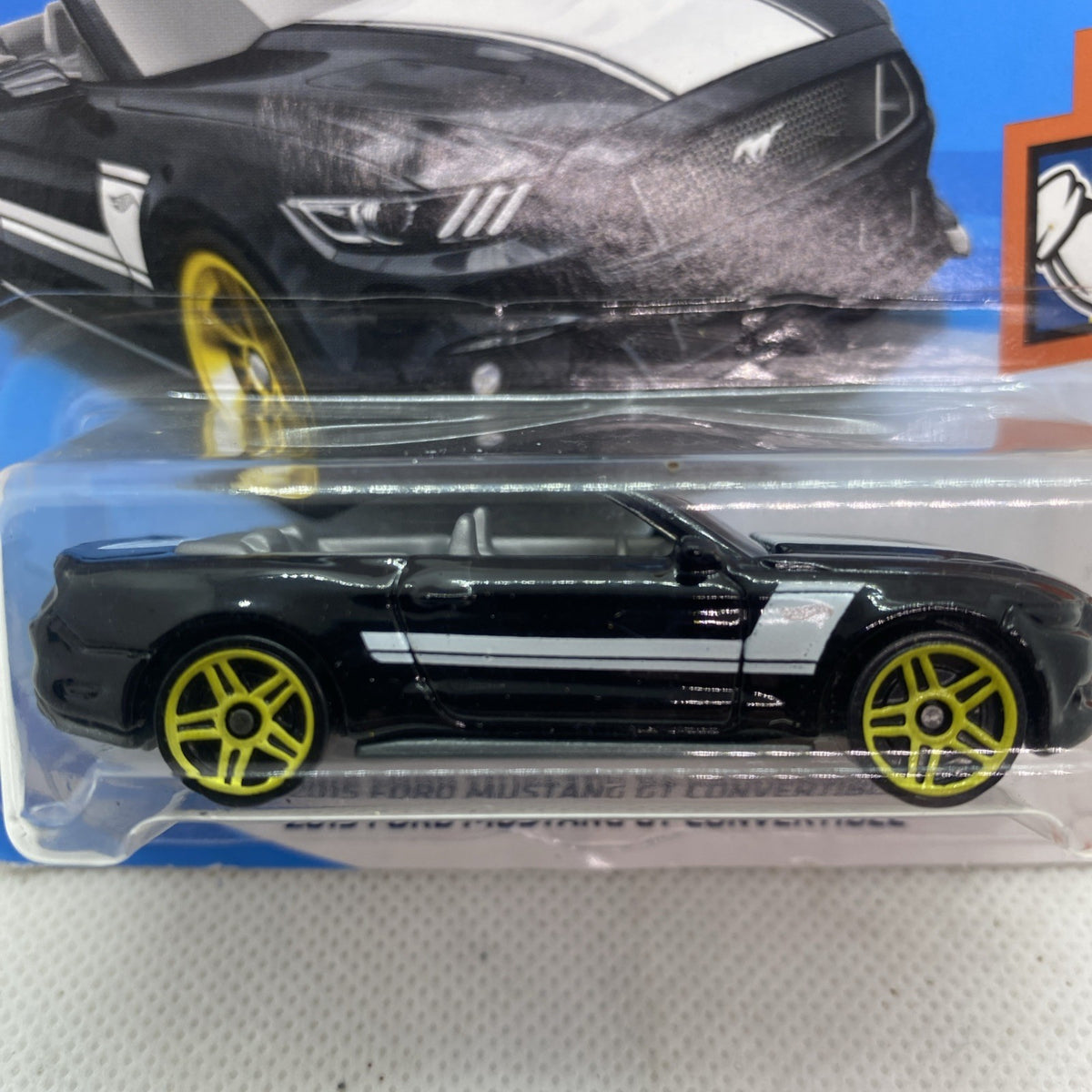 Hot Wheels die-cast black Mustang convertible toy with yellow wheel detail in blister pack