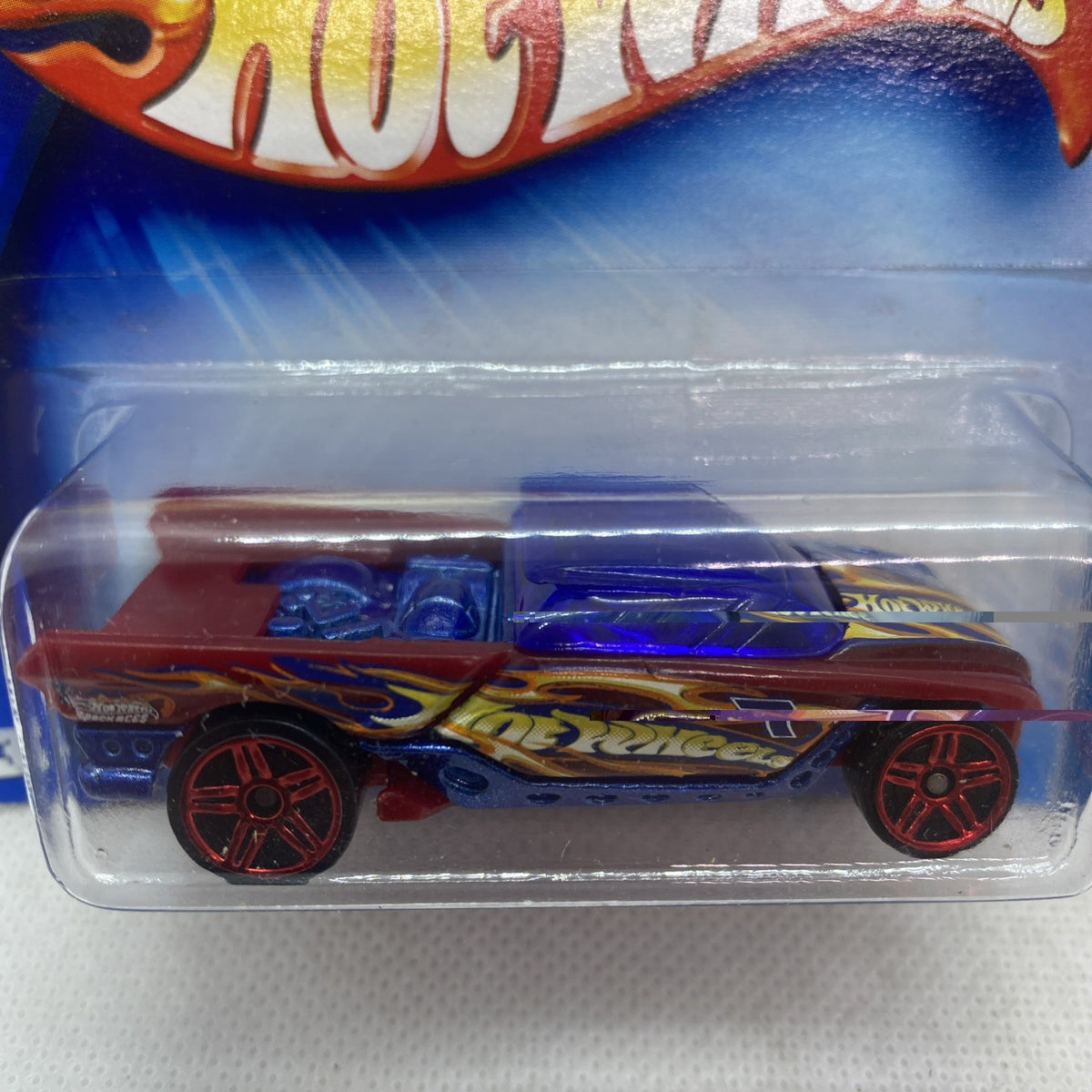Hot Wheels die-cast race car in blister, maroon body with blue flame decal graphics.