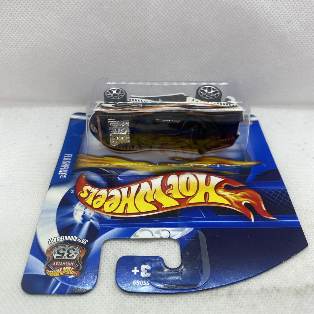 Hot Wheels car blister on blue card, white-and-black race car with black wheels