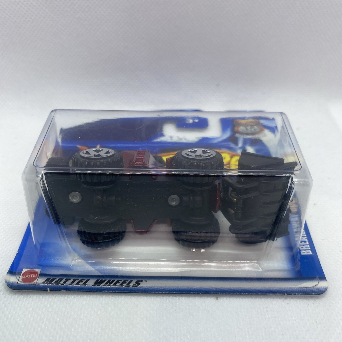 Hot Wheels toy truck underside in clear blister on blue card, rear wheels visible