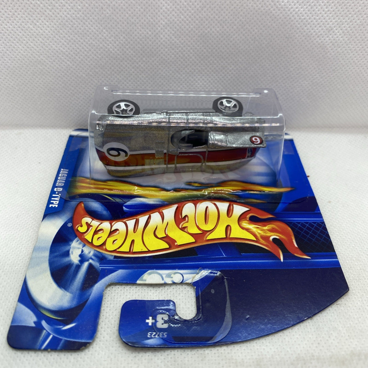 Hot Wheels Jaguar D-Type die-cast car in sealed blister, top view, silver finish