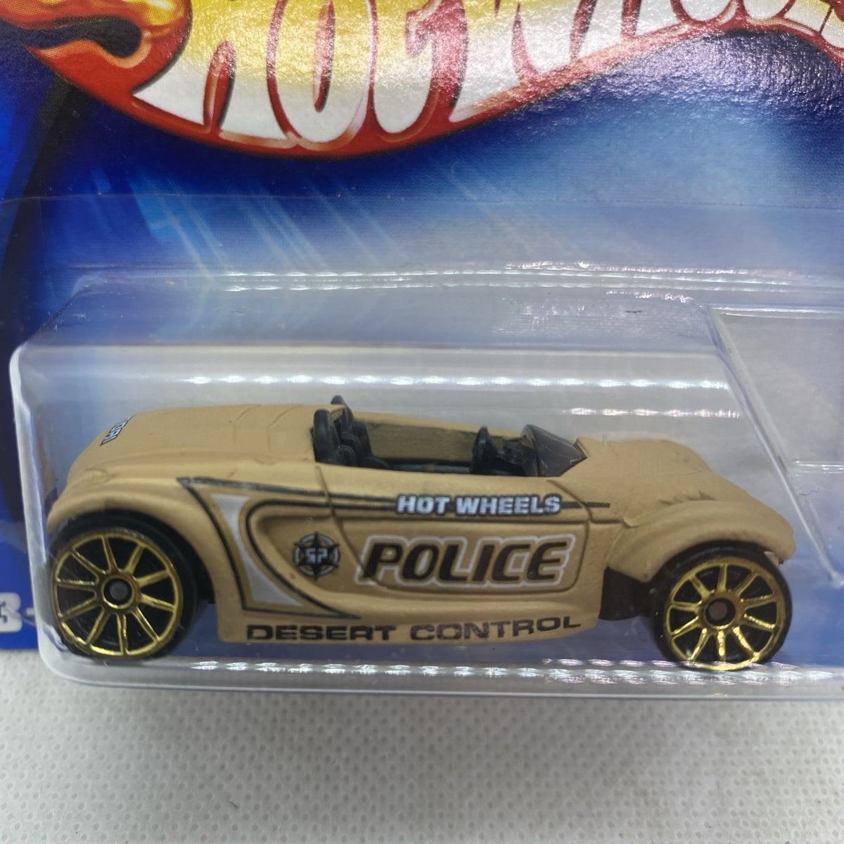 Close-up: beige Hot Wheels police die-cast with 'POLICE' graphic and gold wheels