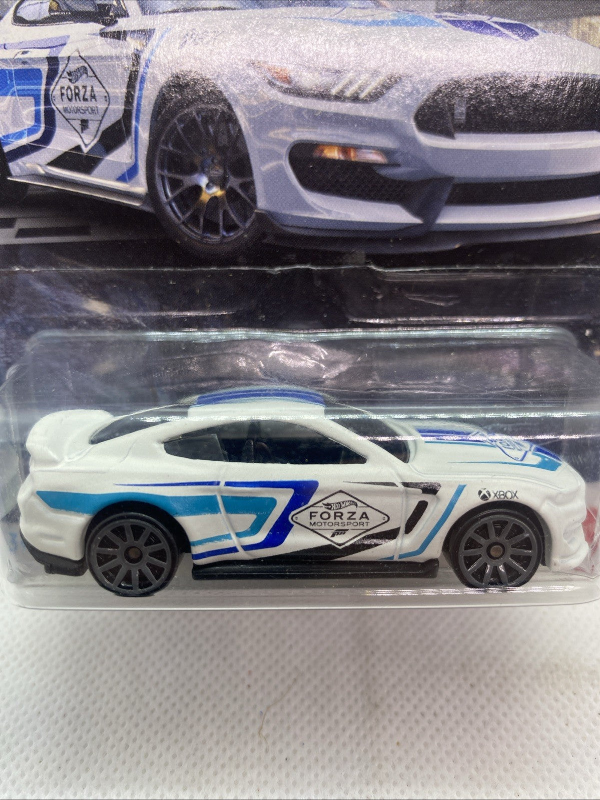 White and blue die-cast toy car in blister window, Forza logo and black wheels