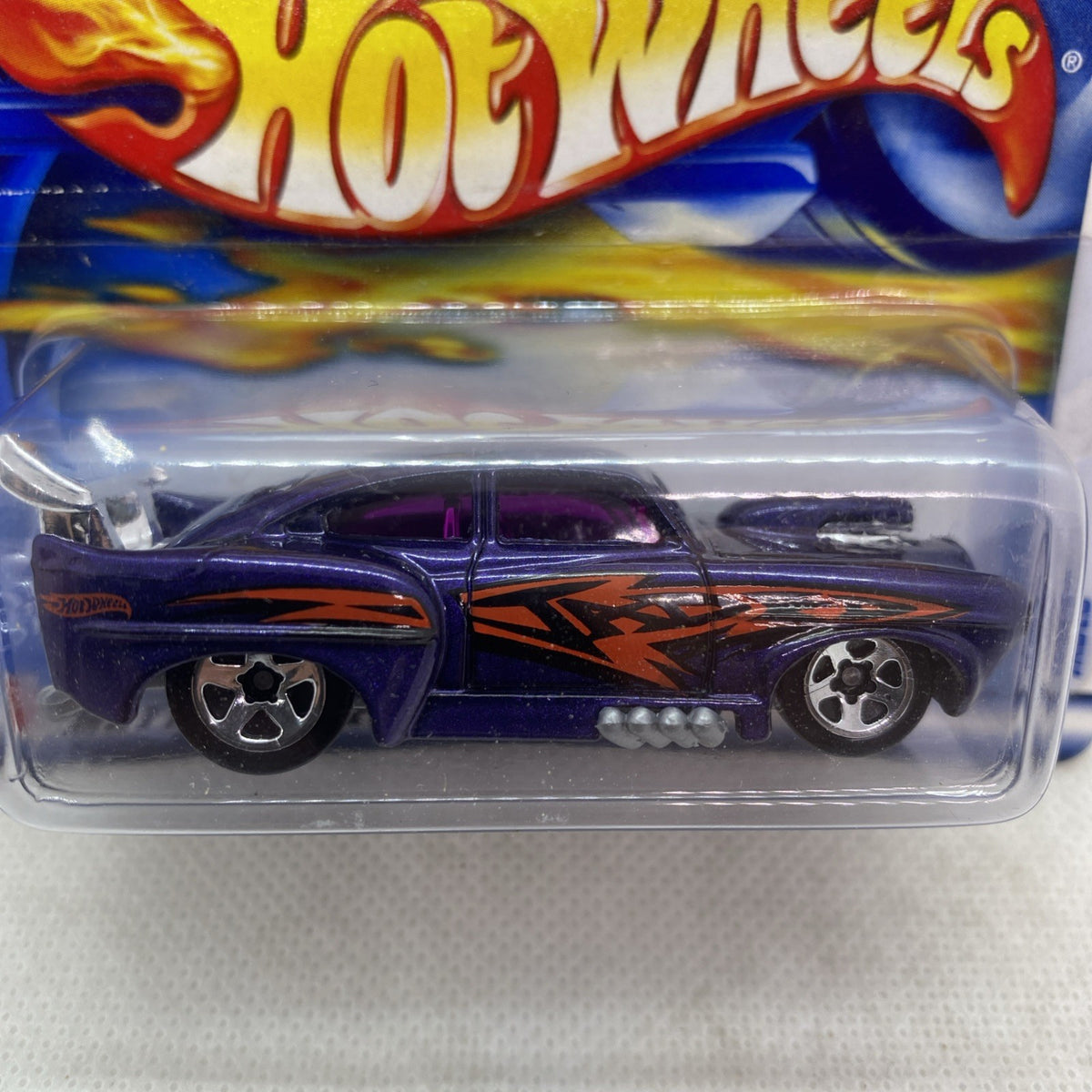 Hot Wheels die-cast car close-up in clear blister, dark purple with orange flames