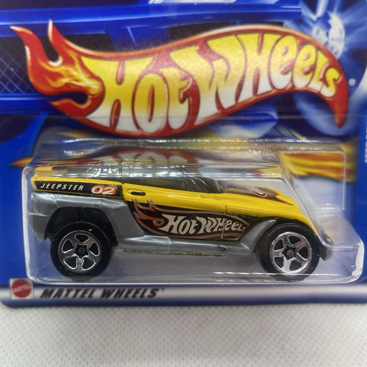 Hot Wheels Jeepster 2002 die-cast car side view with yellow body and Hot Wheels graphics