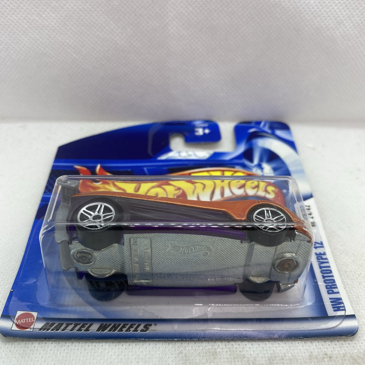 Hot Wheels die-cast car, underside view with wheels, in sealed blister pack