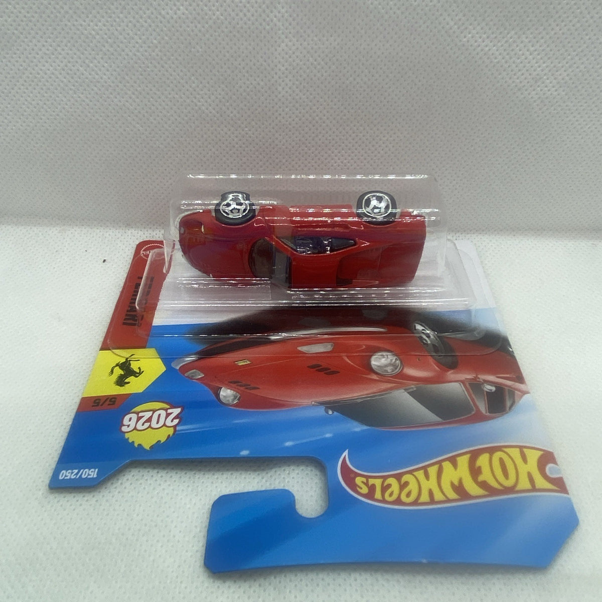 Red die-cast sports car in blister, rear three-quarter view on blue-and-red card.