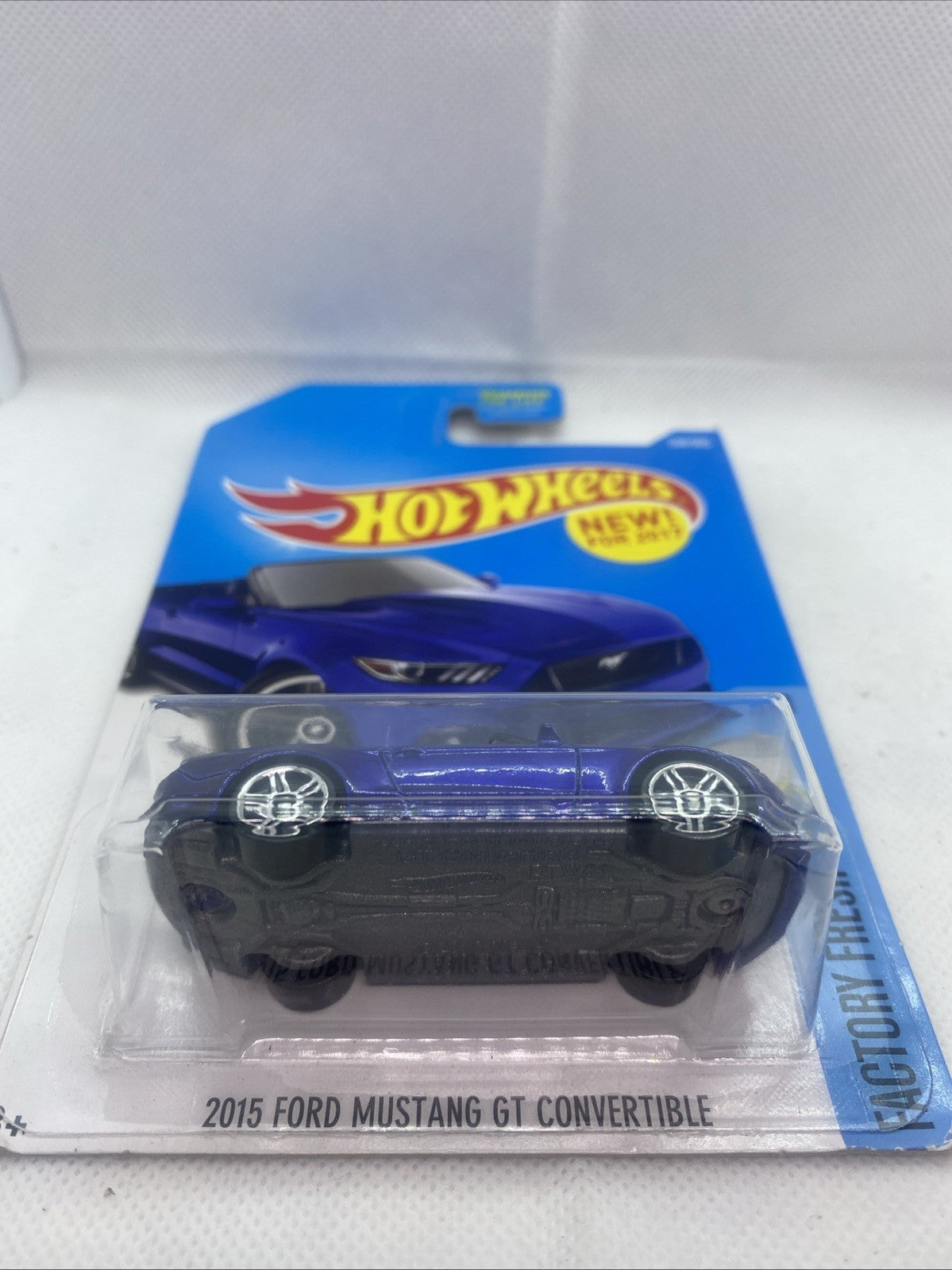 Hot Wheels die-cast toy car in blue blister package, side view inside card
