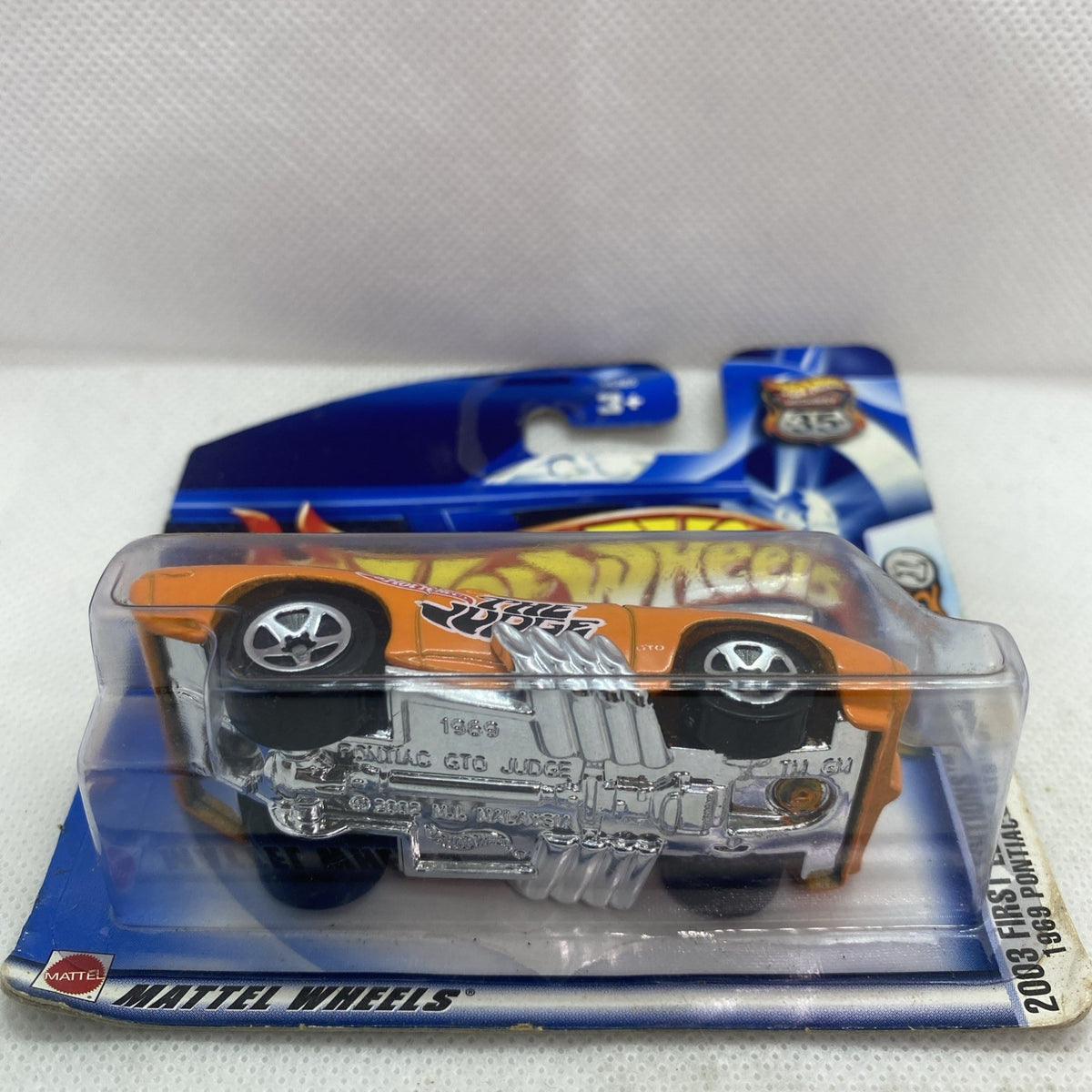Sealed die-cast car toy in blister pack, orange body with chrome engine detail view