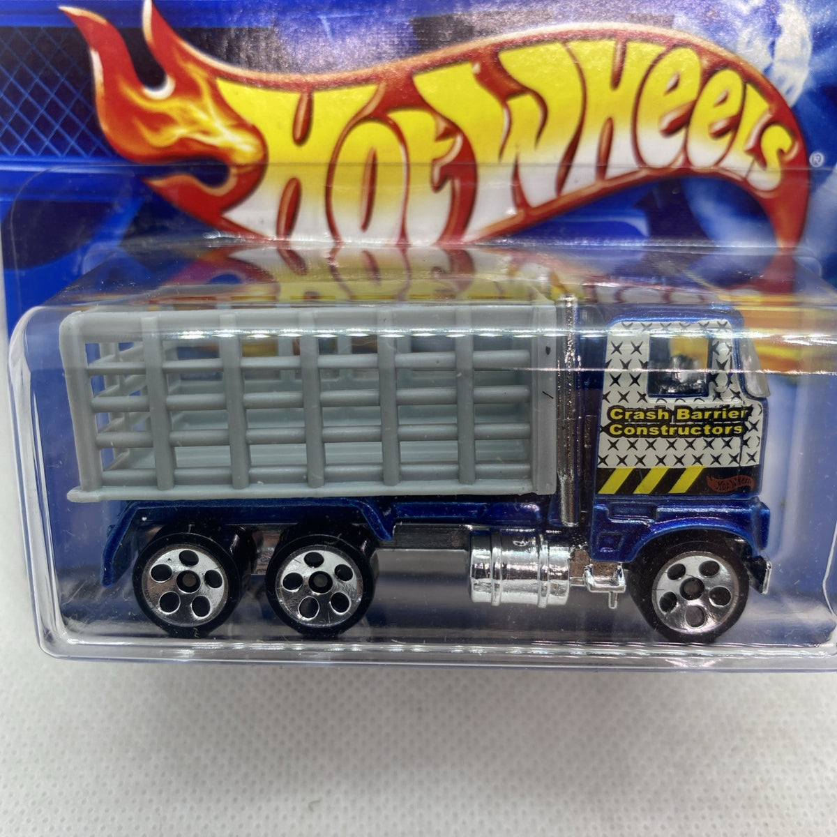Hot Wheels blue Ford stake bed truck in blister, close-up of cargo bed and crash label