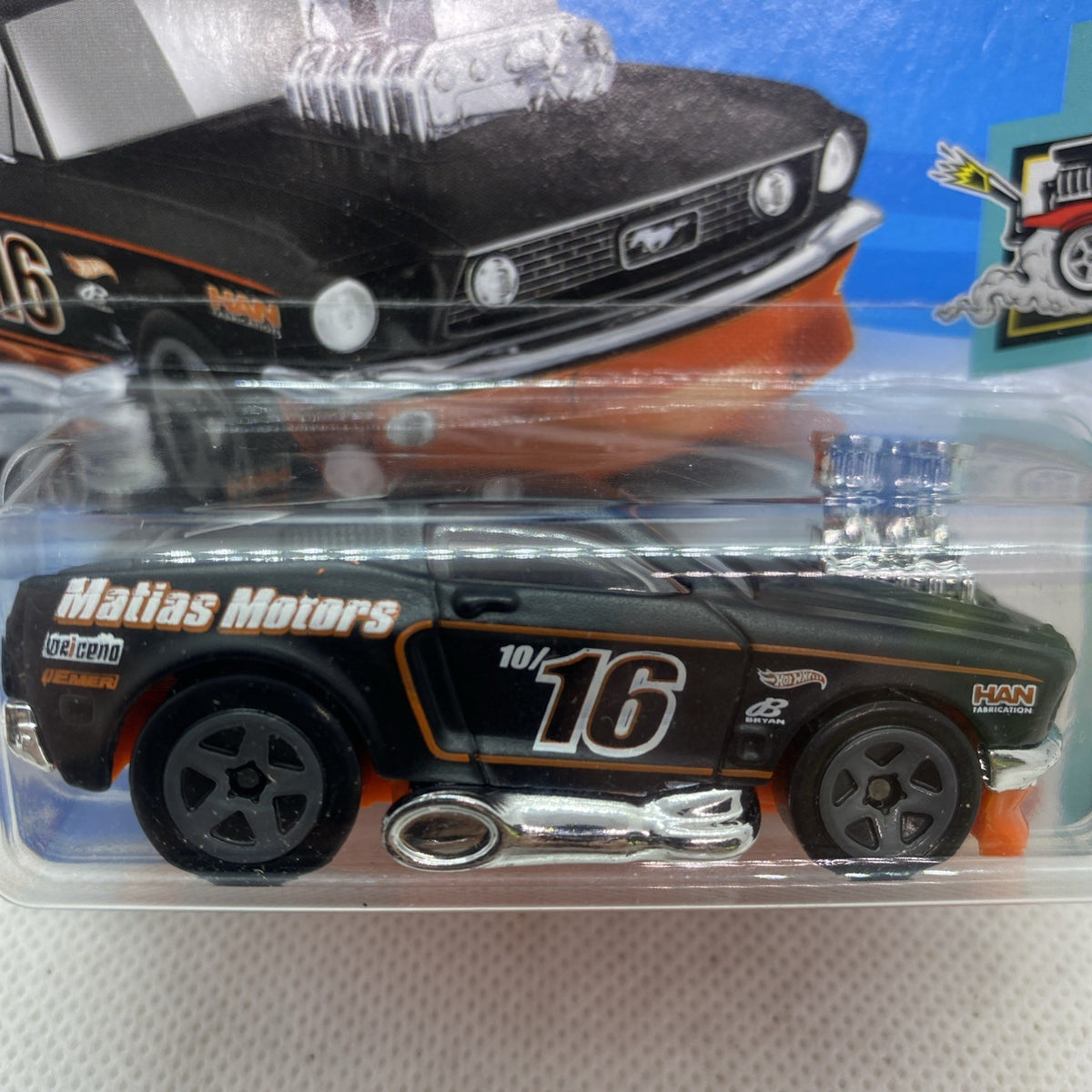 Hot Wheels ’68 Mustang die-cast in blister, close-up of black and orange body and chrome engine