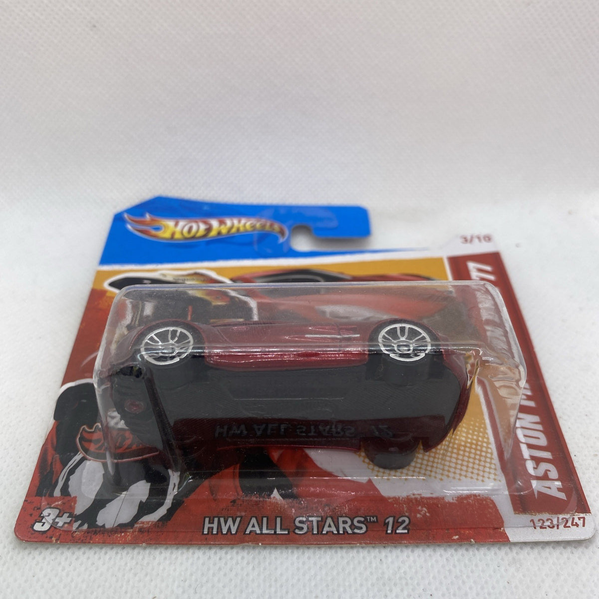 Red Aston Martin One-77 diecast in Hot Wheels card packaging, clear blister