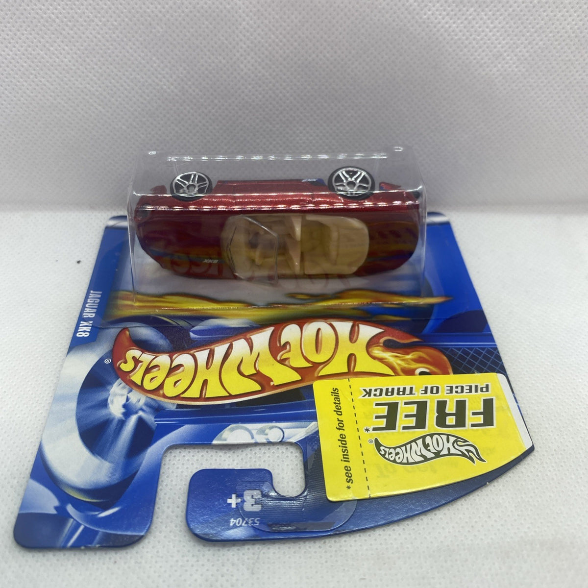 Red die-cast toy car in sealed Hot Wheels blister on track card backing