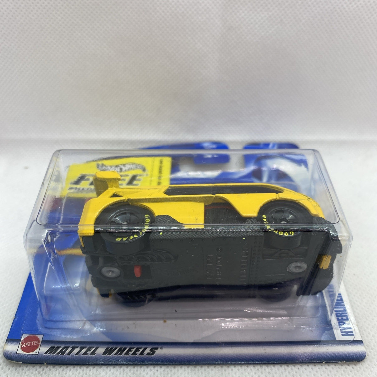 Hot Wheels yellow die-cast car in clear blister, side view on card