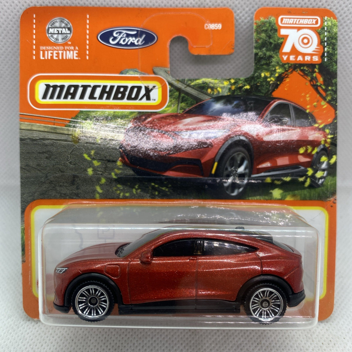 Die-cast toy car in clear blister with orange Matchbox card and red-brown body