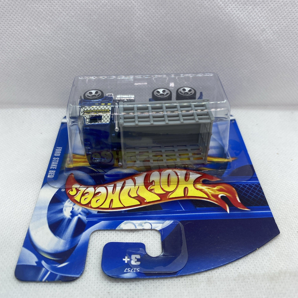 Hot Wheels blue Ford stake bed truck in blister, side view with clear plastic cover