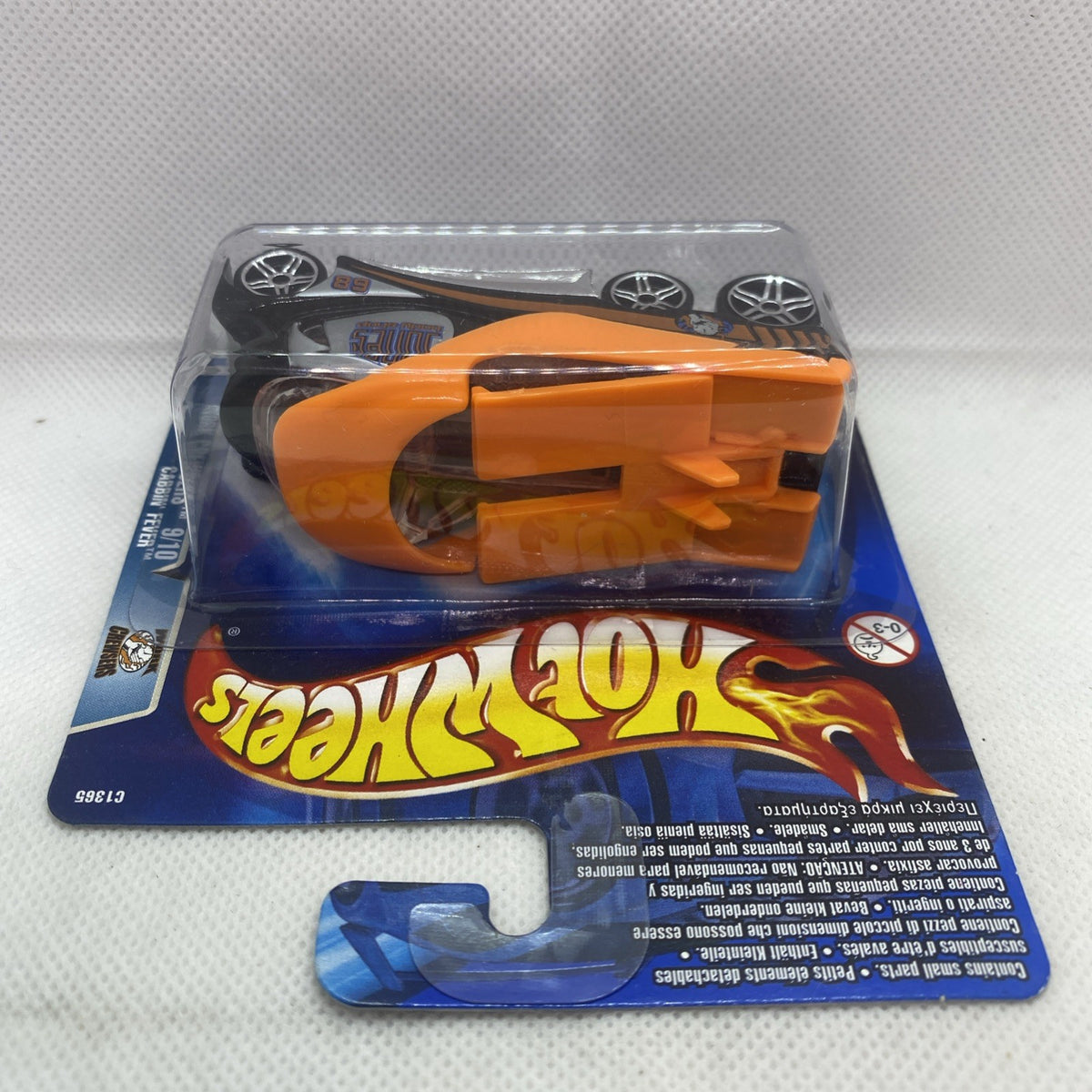 Hot Wheels die-cast toy car in blister pack, orange and black, rear engine detail visible.