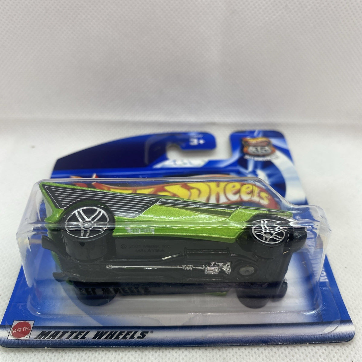 Green Hot Wheels die-cast car in blister card, black base visible from side