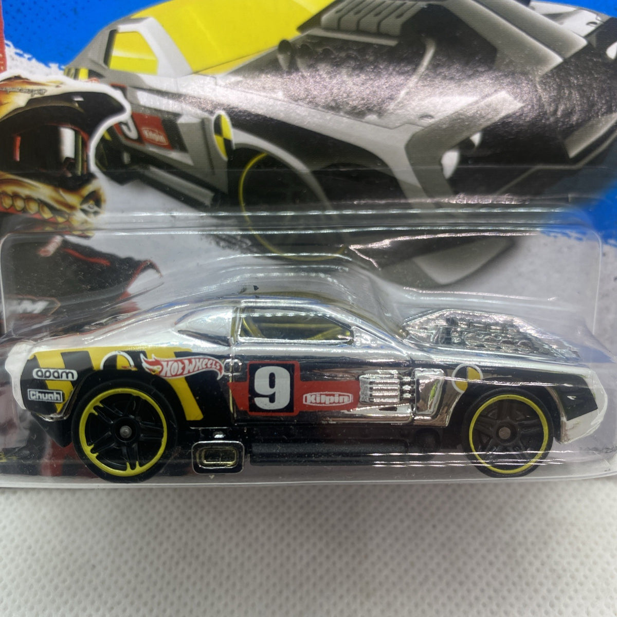 Hot Wheels diecast race car close-up in blister, black with yellow wheels and number 9