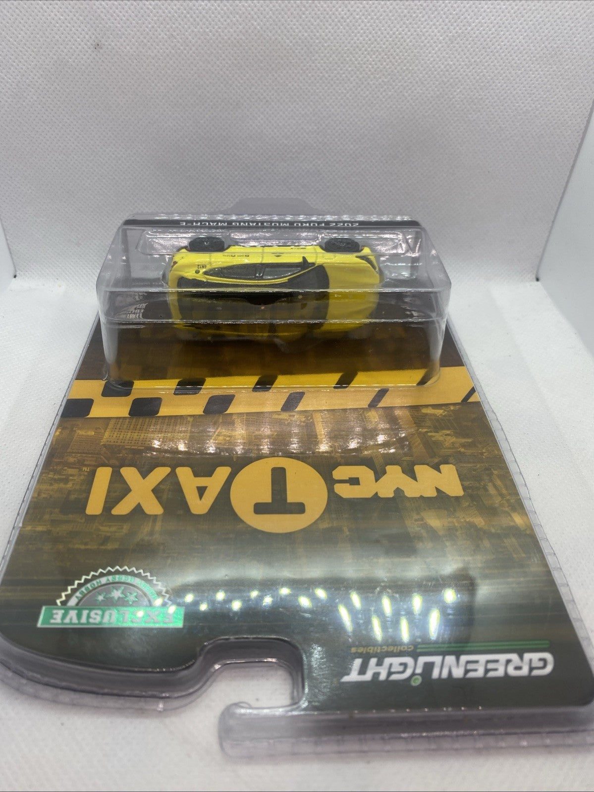 Yellow NYC Taxi die-cast car model viewed from above in blister pack.