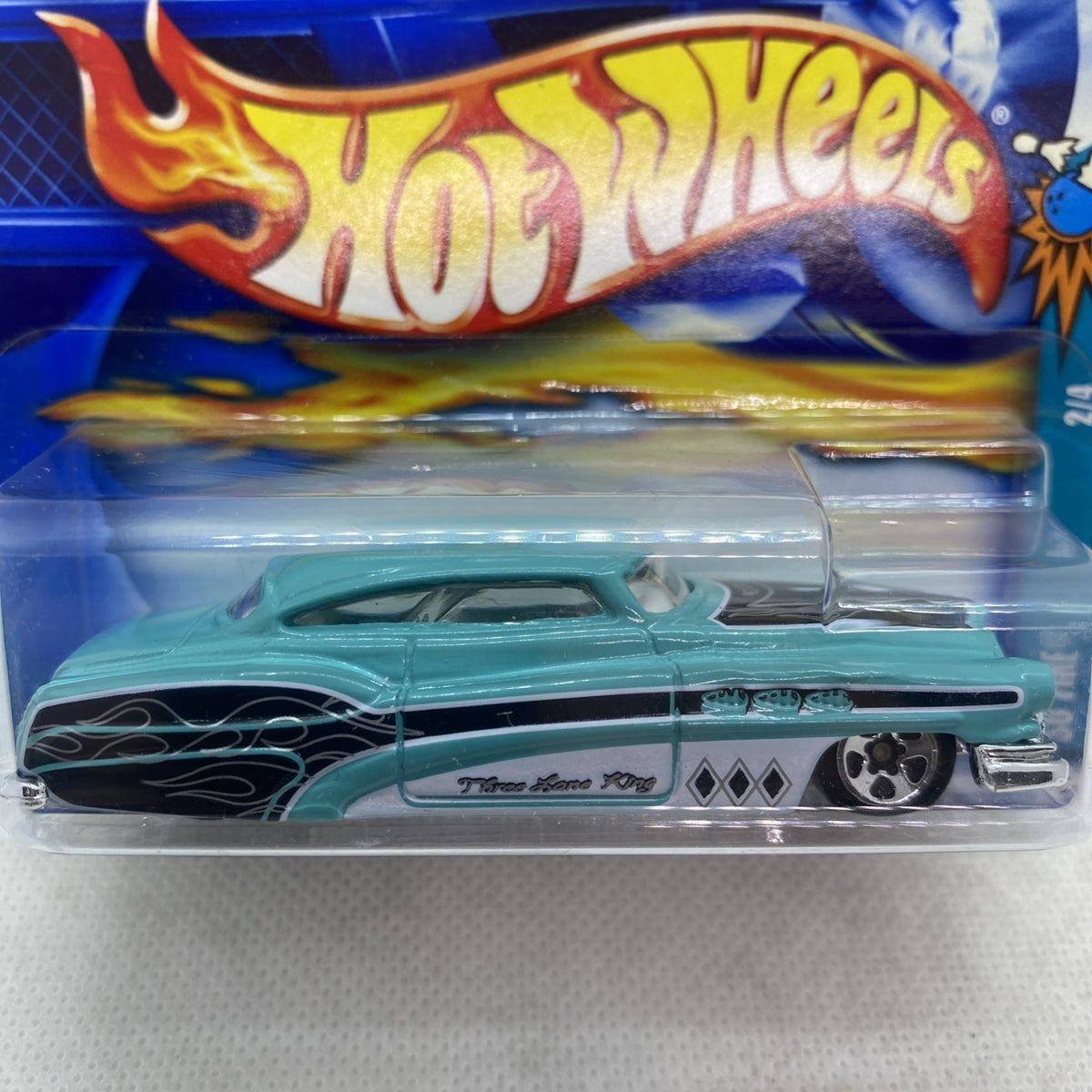 Teal die-cast truck close-up in clear blister, black flame decals on front